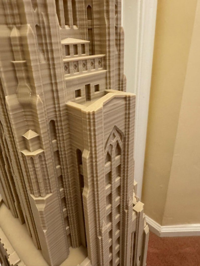 Puede incluir: Primer plano de una maqueta de un edificio alto impreso en 3D con detalles intrincados. El edificio est&aacute; hecho de pl&aacute;stico marr&oacute;n claro y tiene una superficie texturizada. La maqueta es una representaci&oacute;n de un edificio de estilo g&oacute;tico con arcos apuntados y elementos decorativos.