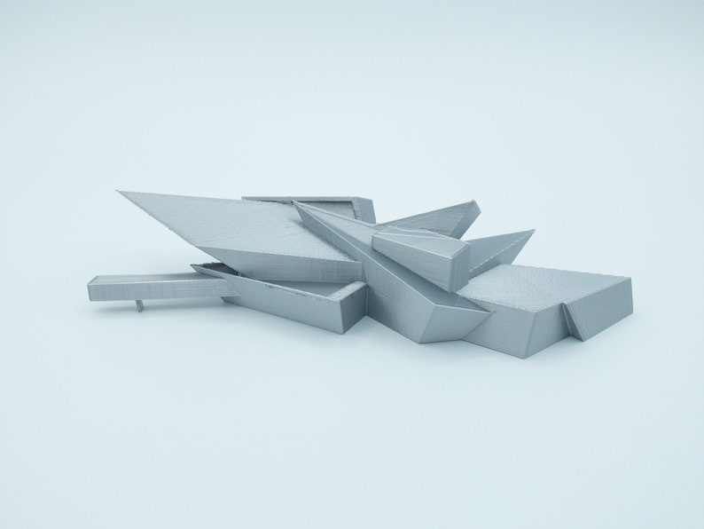 May include: A 3D printed model of a modern building with a geometric design. The model is made of a light gray plastic and has a sharp, angular shape.