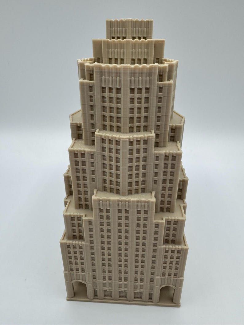 May include: A beige architectural model of a skyscraper with multiple tiers. The model has detailed window patterns and a stepped design, reminiscent of a classic Art Deco building. The structure is made of a light-coloured material.