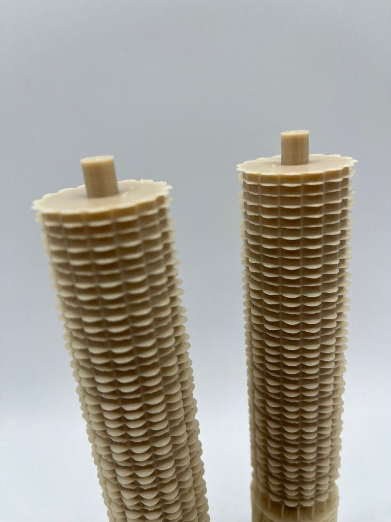 May include: Two beige, cylindrical, decorative items with a textured, scalloped design. The items are made of a lightweight material and have a smooth, rounded top.