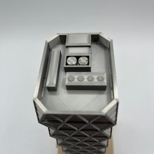 May include: A 3D printed model of a modern skyscraper with a detailed rooftop and a geometric facade.