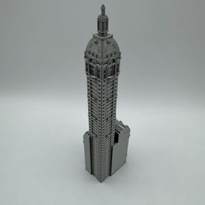 May include: A gray 3D printed model of a tall building with a domed roof and intricate details.
