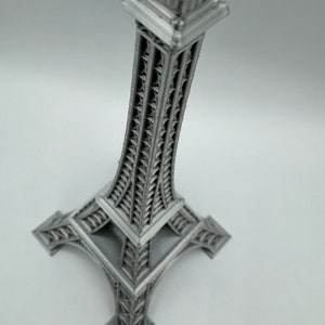May include: A silver metal Eiffel Tower replica with intricate details. The tower is a miniature version of the iconic Parisian landmark.