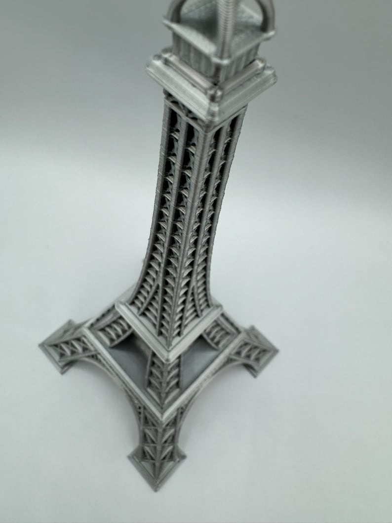 May include: A silver metal Eiffel Tower replica with intricate details. The tower is a miniature version of the iconic Parisian landmark.