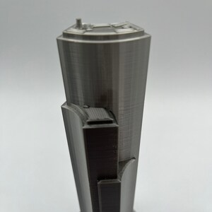 May include: A gray 3D printed model of a skyscraper with a detailed facade and a flat roof.
