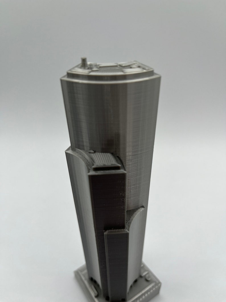 May include: A gray 3D printed model of a skyscraper with a detailed facade and a flat roof.