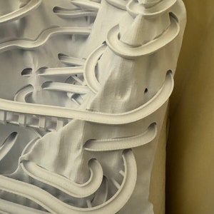 May include: White 3D printed model of a mountain with a complex network of winding tracks and tunnels.
