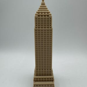 Puede incluir: Un modelo en miniatura beige de un rascacielos con un techo puntiagudo y muchas ventanas.
