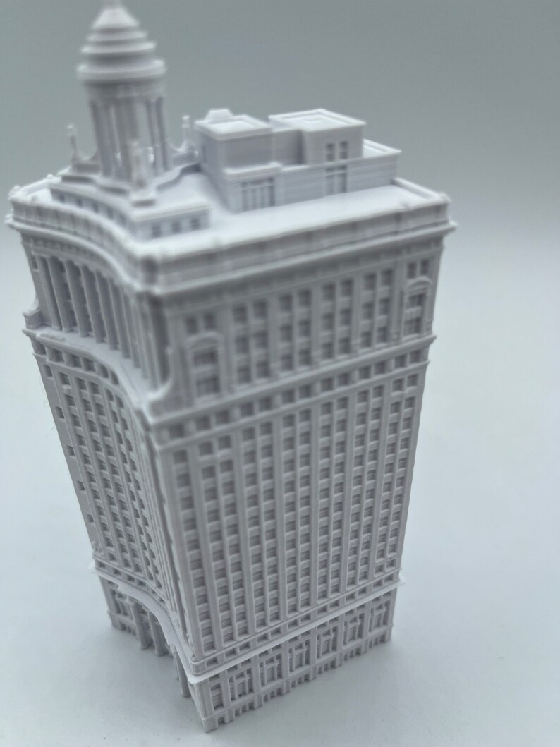 Op de afbeelding: Een wit 3D-geprint model van een hoog gebouw met een gebogen gevel en een gedetailleerd dak.