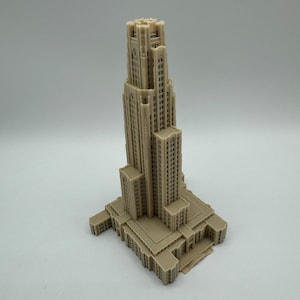 May include: A detailed 3D printed model of a tall, beige building with a tower and a large base. The building has many windows and intricate details.
