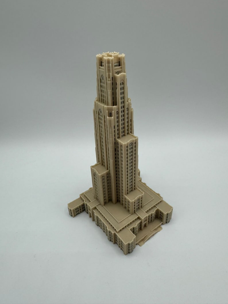 May include: A detailed 3D printed model of a tall, beige building with a tower and a large base. The building has many windows and intricate details.