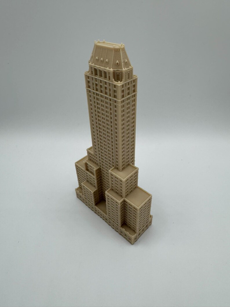 Może przedstawiać: Beżowy miniaturowy model wieżowca z szczeg&oacute;łowymi elementami architektonicznymi. Budynek ma wielopoziomową konstrukcję z licznymi oknami i szczeg&oacute;łowym dachem. Model jest reprezentacją znanego budynku.