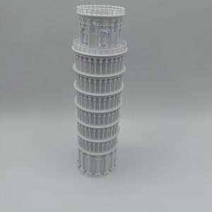 May include: A white 3D printed model of the Leaning Tower of Pisa. The model is detailed with arches and columns.