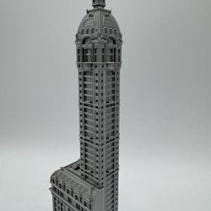 May include: A gray 3D printed model of a tall, ornate building with a domed roof.