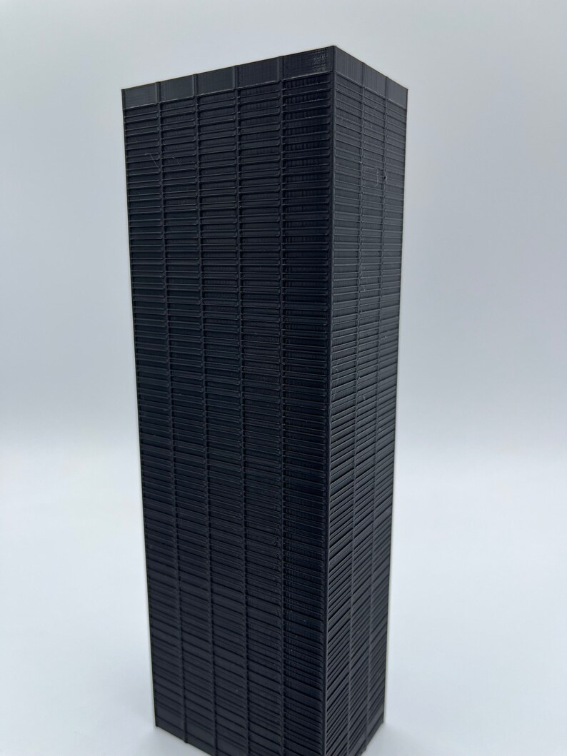 May include: A black 3D printed model of a skyscraper with a grid pattern on the facade.