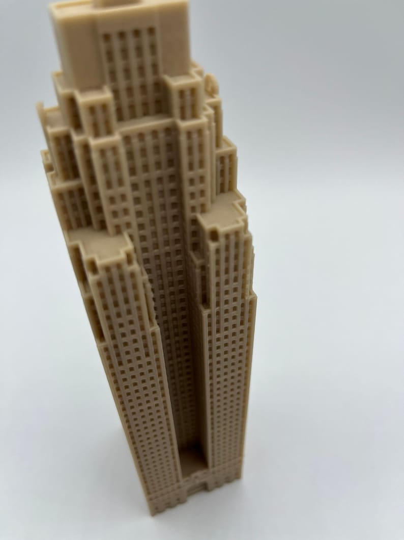 May include: A beige miniature model of a tall skyscraper with many windows.