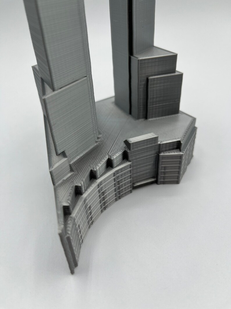 Op de afbeelding: Een 3D-geprint model van een moderne wolkenkrabber met een gebogen basis en een hoge, rechthoekige toren.