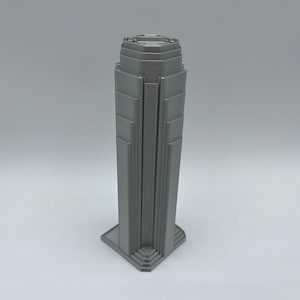 May include: A gray 3D printed model of a skyscraper with a detailed facade.