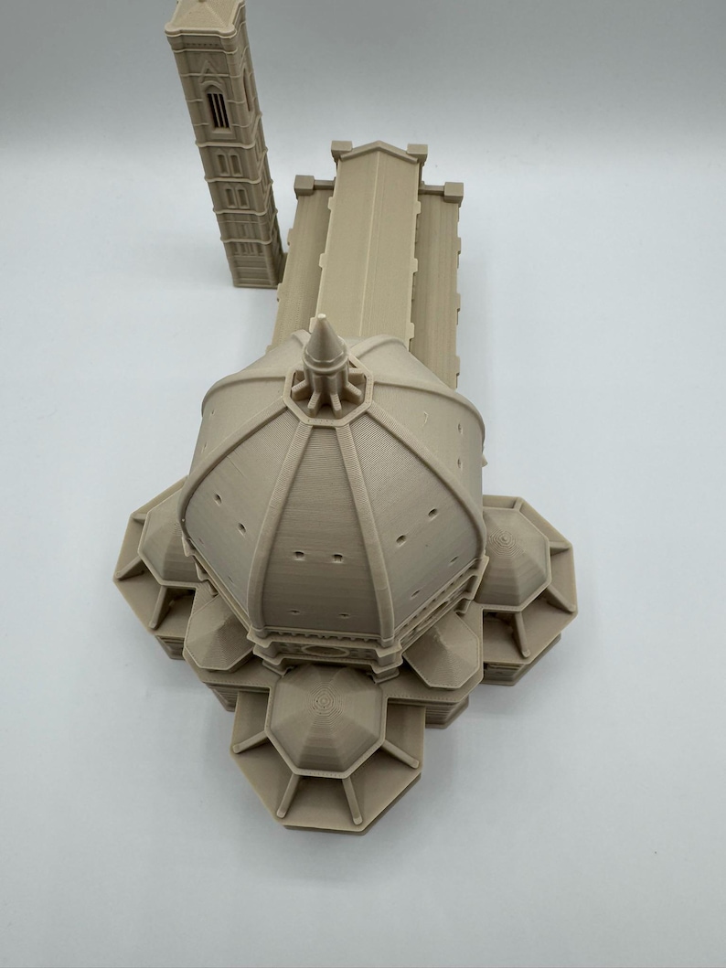 May include: A beige 3D-printed model of the Florence Cathedral, featuring the iconic dome and bell tower. The model showcases architectural details, including the dome's design and the tower's windows. The model is a detailed replica of the famous Italian landmark.