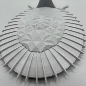 May include: White 3D printed geometric design with a raised center and a scalloped edge.
