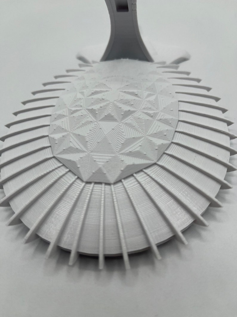 May include: White 3D printed geometric design with a raised center and a scalloped edge.