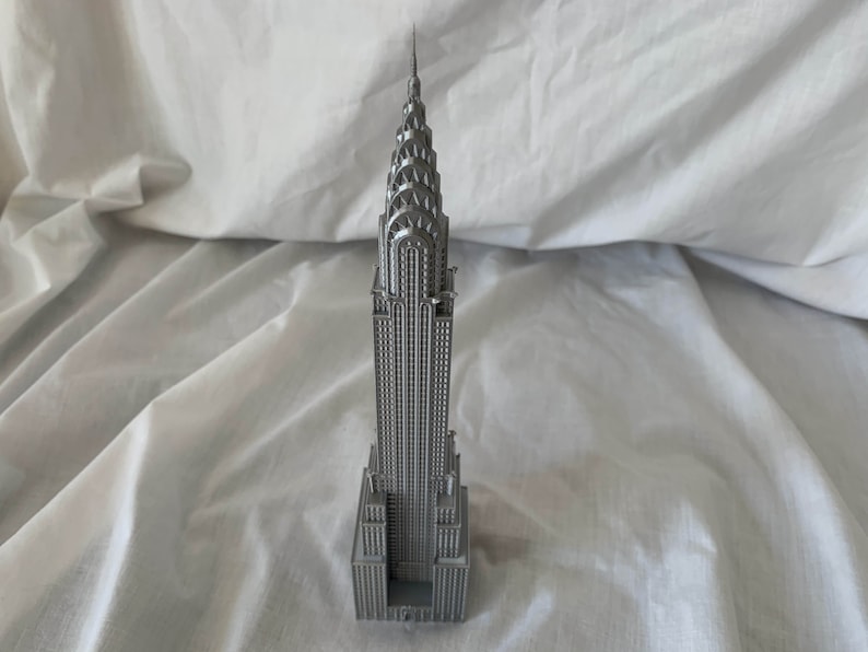 Puede incluir: Una maqueta de plata del edificio Chrysler, un famoso rascacielos de la ciudad de Nueva York.