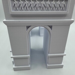 Może przedstawiać: Biały model 3D Łuku Triumfalnego. Model architektoniczny posiada centralny łuk i prostokątny fryz z rzędem małych ludzkich postaci. Model jest szczeg&oacute;łową repliką słynnego paryskiego zabytku.