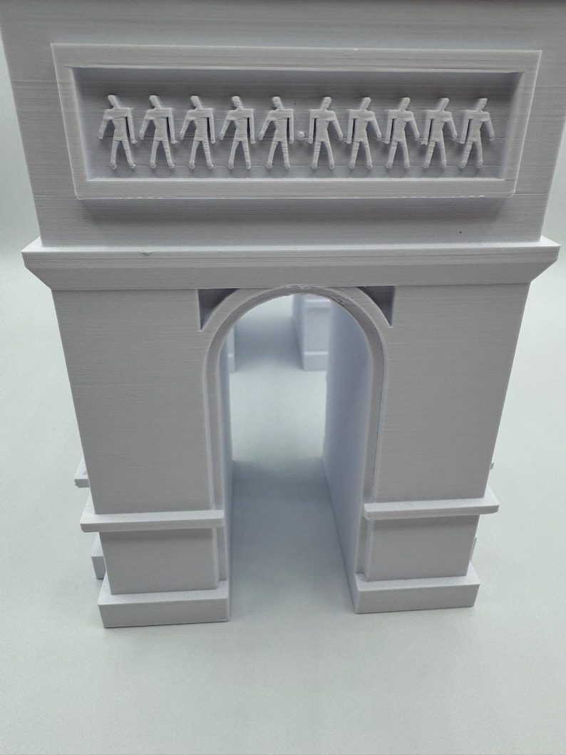 Może przedstawiać: Biały model 3D Łuku Triumfalnego. Model architektoniczny posiada centralny łuk i prostokątny fryz z rzędem małych ludzkich postaci. Model jest szczeg&oacute;łową repliką słynnego paryskiego zabytku.