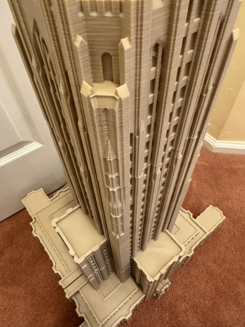 Puede incluir: Un modelo impreso en 3D detallado de un edificio alto con un techo puntiagudo y detalles intrincados. El modelo est&aacute; hecho de pl&aacute;stico marr&oacute;n claro y tiene una superficie texturizada.