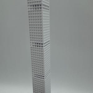 May include: A grey model of a skyscraper with a grid-like facade. The building is rectangular and tapers slightly towards the top. The model is a detailed representation of a modern architectural design.