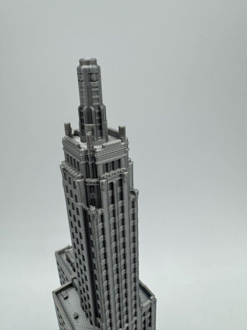 May include: A 3D printed model of a tall, grey building with a pointed roof and many windows.
