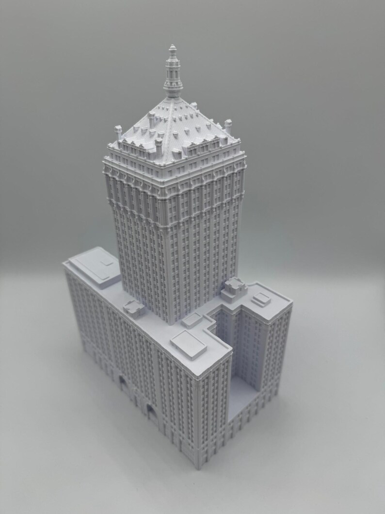Puede incluir: Modelo arquitect&oacute;nico blanco detallado de un rascacielos. El modelo presenta una torre central alta con una parte superior decorativa y una base m&aacute;s ancha con m&uacute;ltiples niveles. El edificio tiene muchas ventanas y detalles arquitect&oacute;nicos.