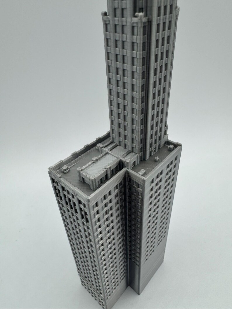 May include: A grey 3D printed model of a tall skyscraper building with a flat roof.