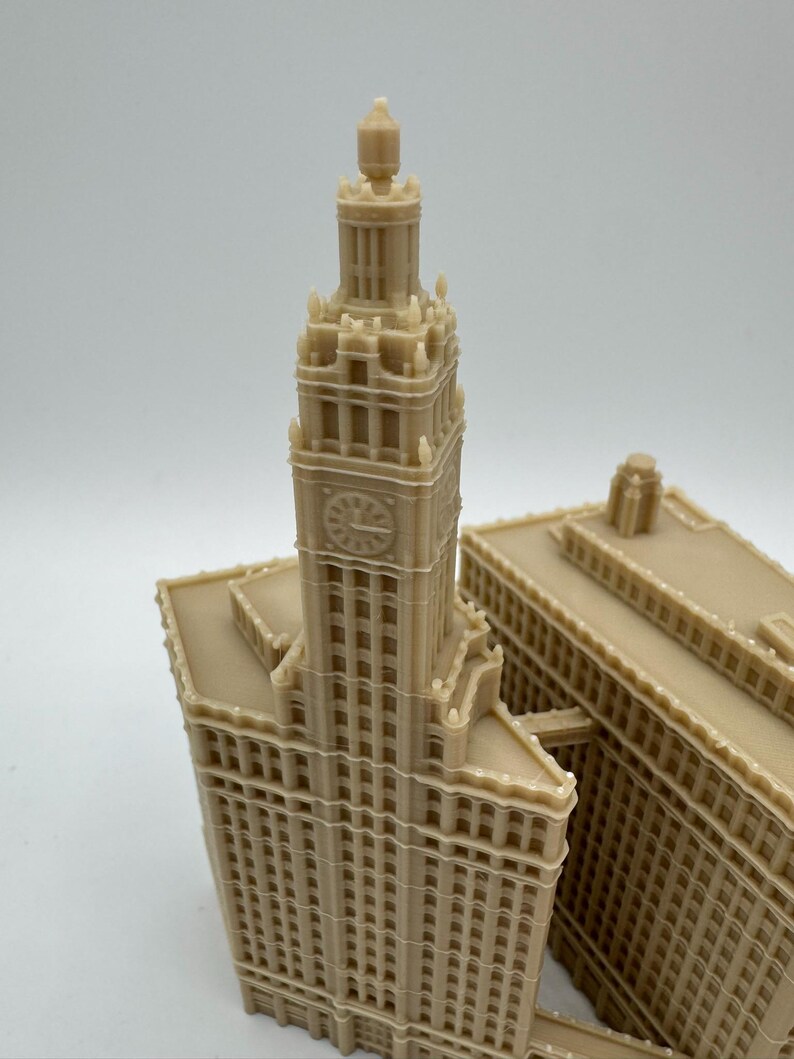 May include: A beige miniature of a tall building with a clock tower. The building has many windows and architectural details. The model is likely a replica of a famous landmark.