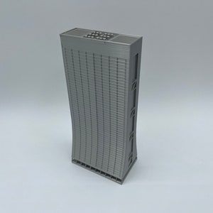 May include: A gray, 3D printed model of a tall, modern skyscraper with a curved facade and a flat roof.
