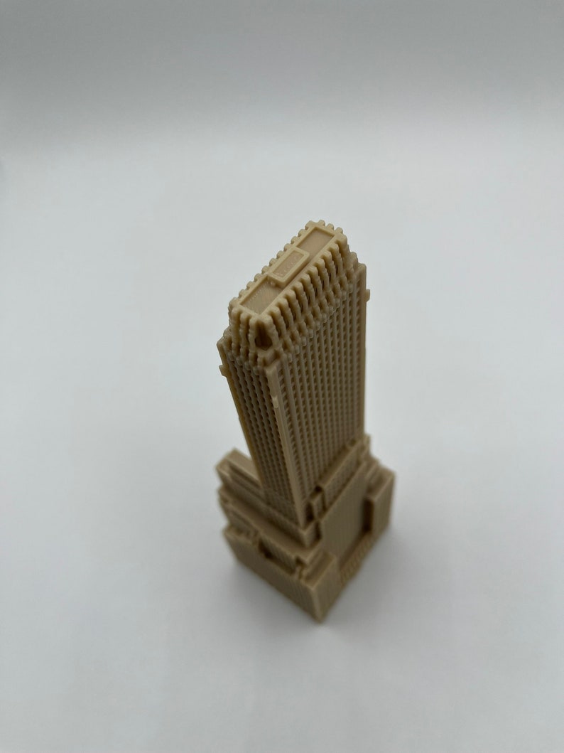 May include: A beige miniature model of a skyscraper with a detailed facade and a flat roof.