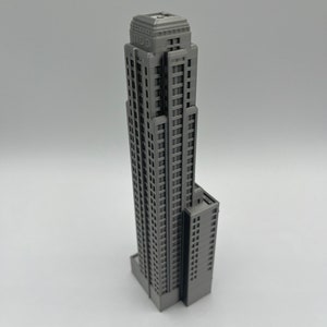 May include: A gray 3D printed model of a tall skyscraper with a rectangular base and a flat roof.