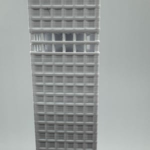 May include: A 3D-printed model of a skyscraper. The building is a light grey colour and features a grid-like pattern of windows and structural elements. The model is a detailed representation of a modern architectural design.