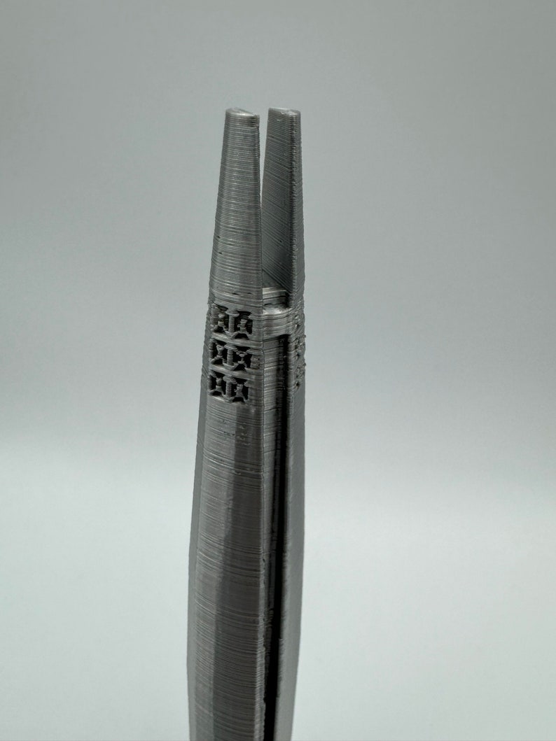 May include: A pair of silver-colored metal tweezers with a textured surface and a pointed tip.