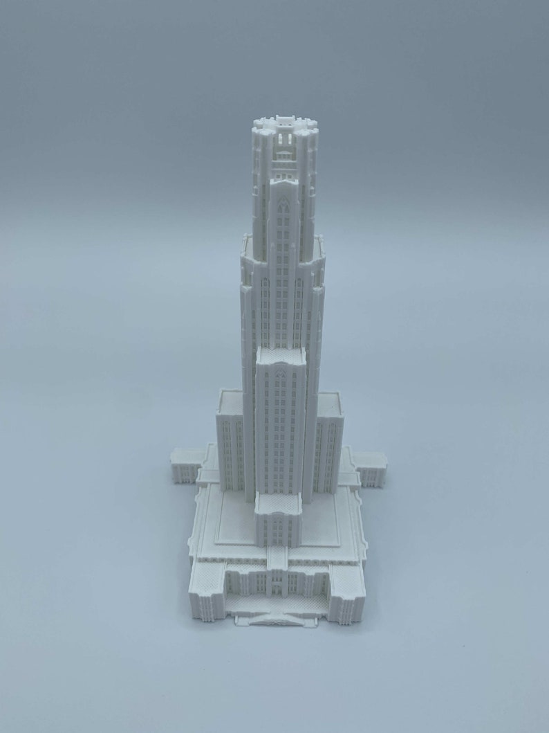 May include: A white 3D printed model of a tall building with a pointed roof and many windows.