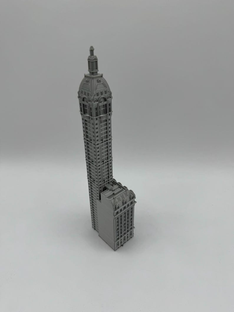 May include: A gray 3D printed model of a tall building with a domed roof.