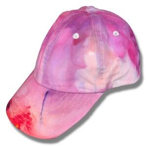 Op de afbeelding: Een roze en paarse tie-dye baseballpet met een gebogen klep.