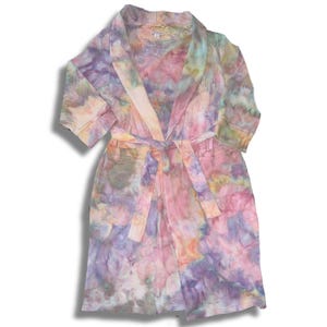 May include: A tie-dye patterned robe in pastel colors of pink, purple, yellow, and blue. The robe has a shawl collar, a waist tie, and short sleeves. The fabric appears to be a lightweight waffle weave.