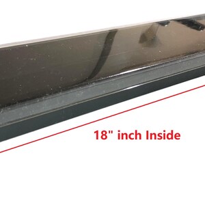 Op de afbeelding: Een zwarte rechthoekige container met een doorzichtig deksel. De binnenafmetingen zijn 45,7 cm lang, 2,5 cm diep en 6,4 cm breed. De container is ontworpen om items in te bewaren.