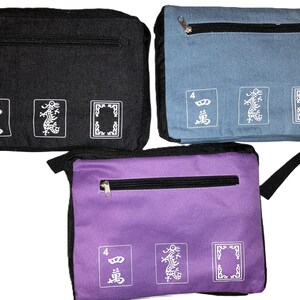 May include: Three rectangular fabric bags in black, blue, and purple. Each bag has a zippered top pocket and three white graphic designs on the front. The designs include the number 4, a dragon, and a framed shape. The bags have black straps.