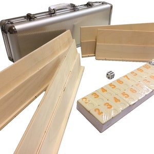 May include: A silver aluminum carrying case with a set of wooden dominoes, a dice, and wooden racks. The dominoes are numbered 1 through 10 and have orange numbers on a cream background.