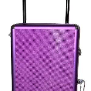May include: A purple rolling makeup case with a textured surface. It has a black telescoping handle and silver-colored hardware. The case is designed for cosmetics and beauty supplies.