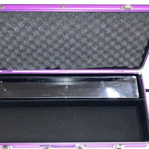May include: Open purple aluminum case with a black interior. The top of the case has a foam lining. The bottom of the case has a black felt lining. A clear plastic tray is in the middle of the case.