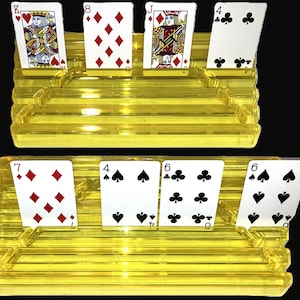 May include: Two tiered yellow translucent plastic card holders designed to display playing cards. The top holder displays the King of Hearts, 8 of Diamonds, Jack of Diamonds, and 4 of Clubs. The bottom holder displays the 7 of Diamonds, 4 of Spades, 6 of Clubs, and 6 of Spades.