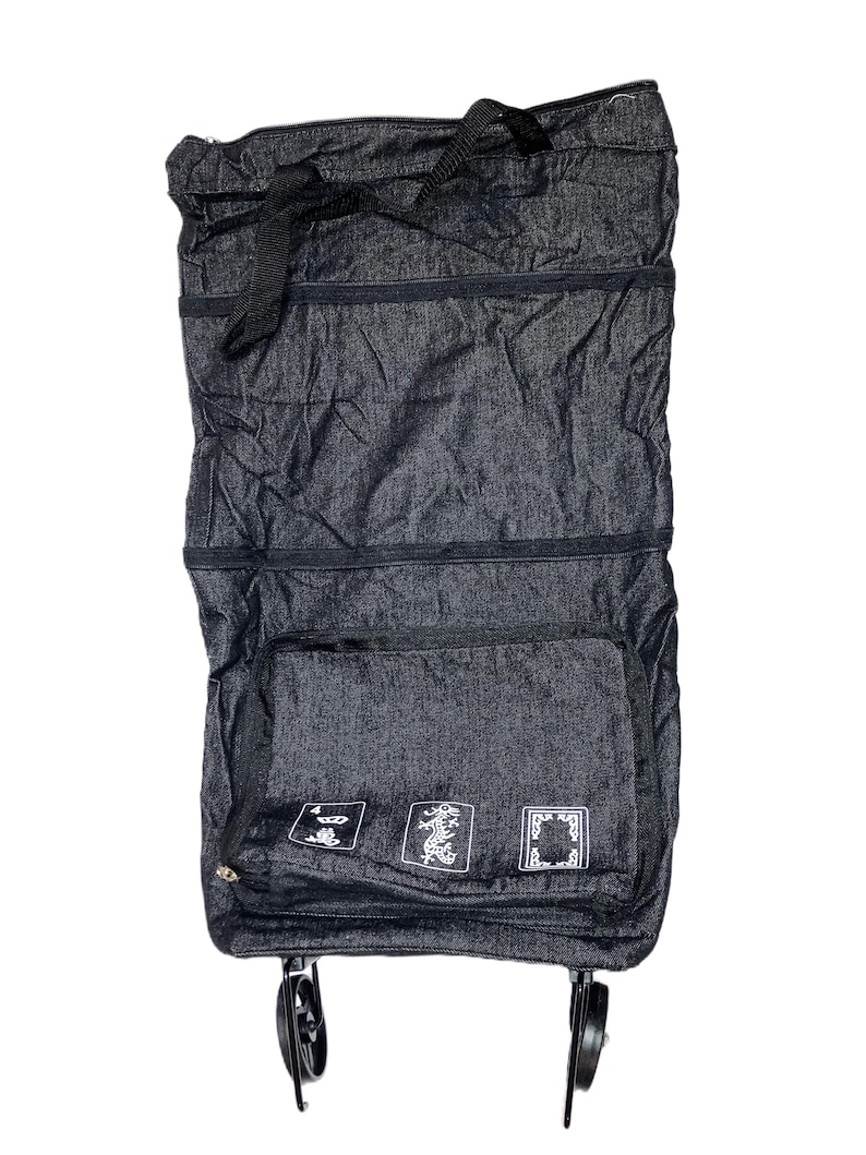 May include: A dark gray, foldable shopping cart with a black handle and wheels. The cart has a large front pocket with three white decorative designs. The cart is made of a textured fabric and is designed for easy storage and transport.